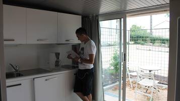 A modern kitchen with white cabinets, a coffee maker, and a person preparing food.