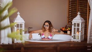 A person sitting in a bathtub with white lanterns and candles on the sides. - Arwen Hotel (Fethiye)