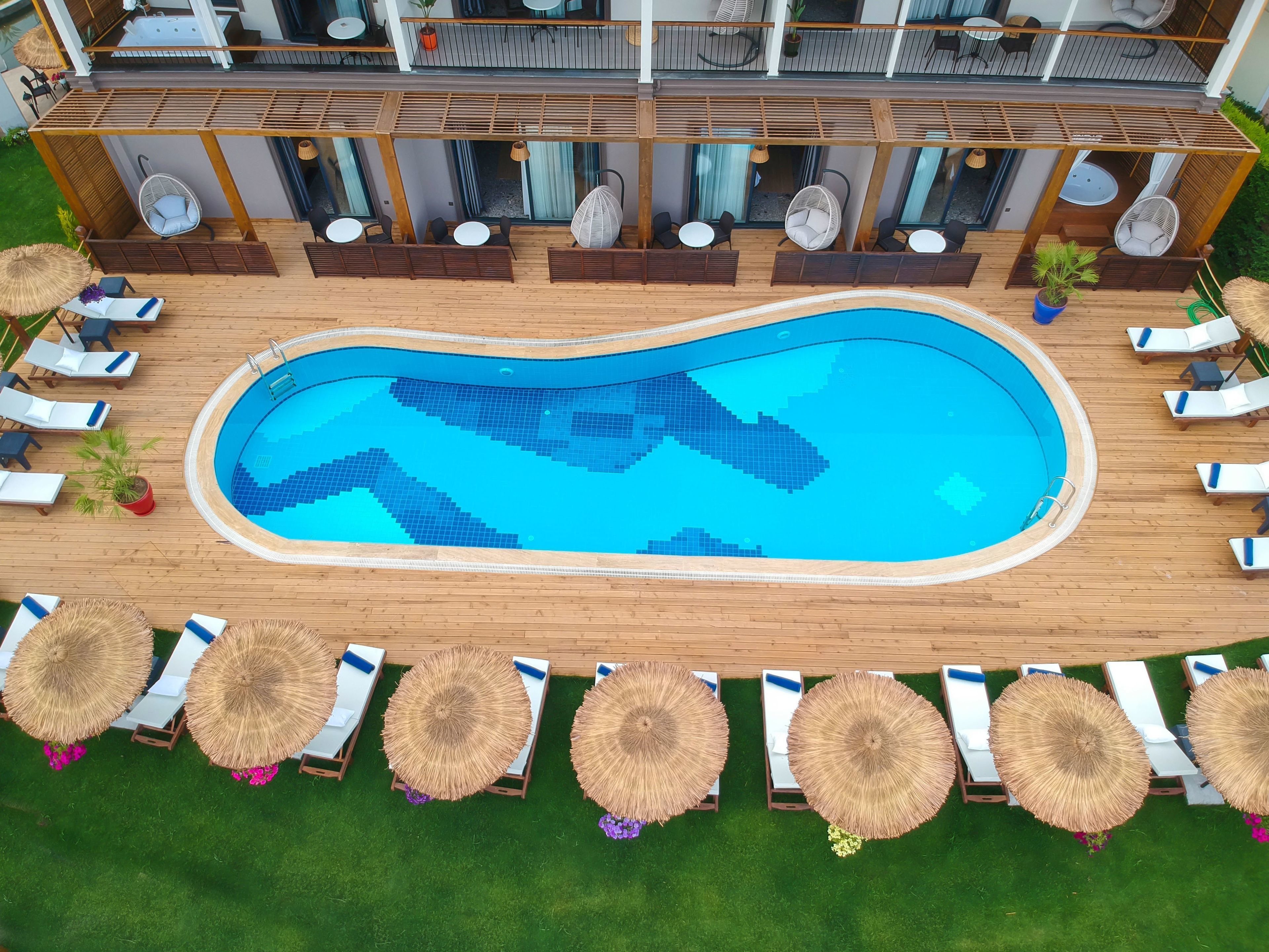 An aerial view of a hotel with a swimming pool, lounge chairs, and a deck area.