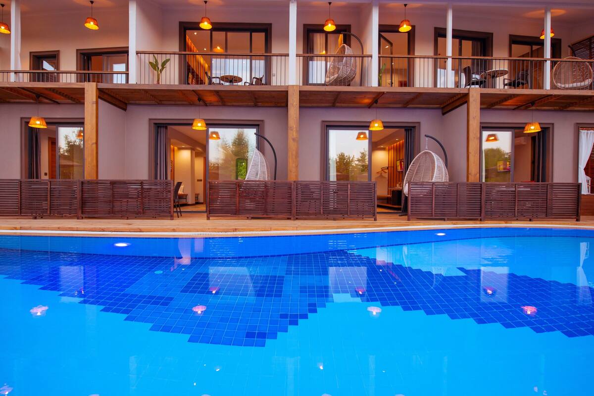 Un hotel con piscina, balcones de madera y muebles modernos.
