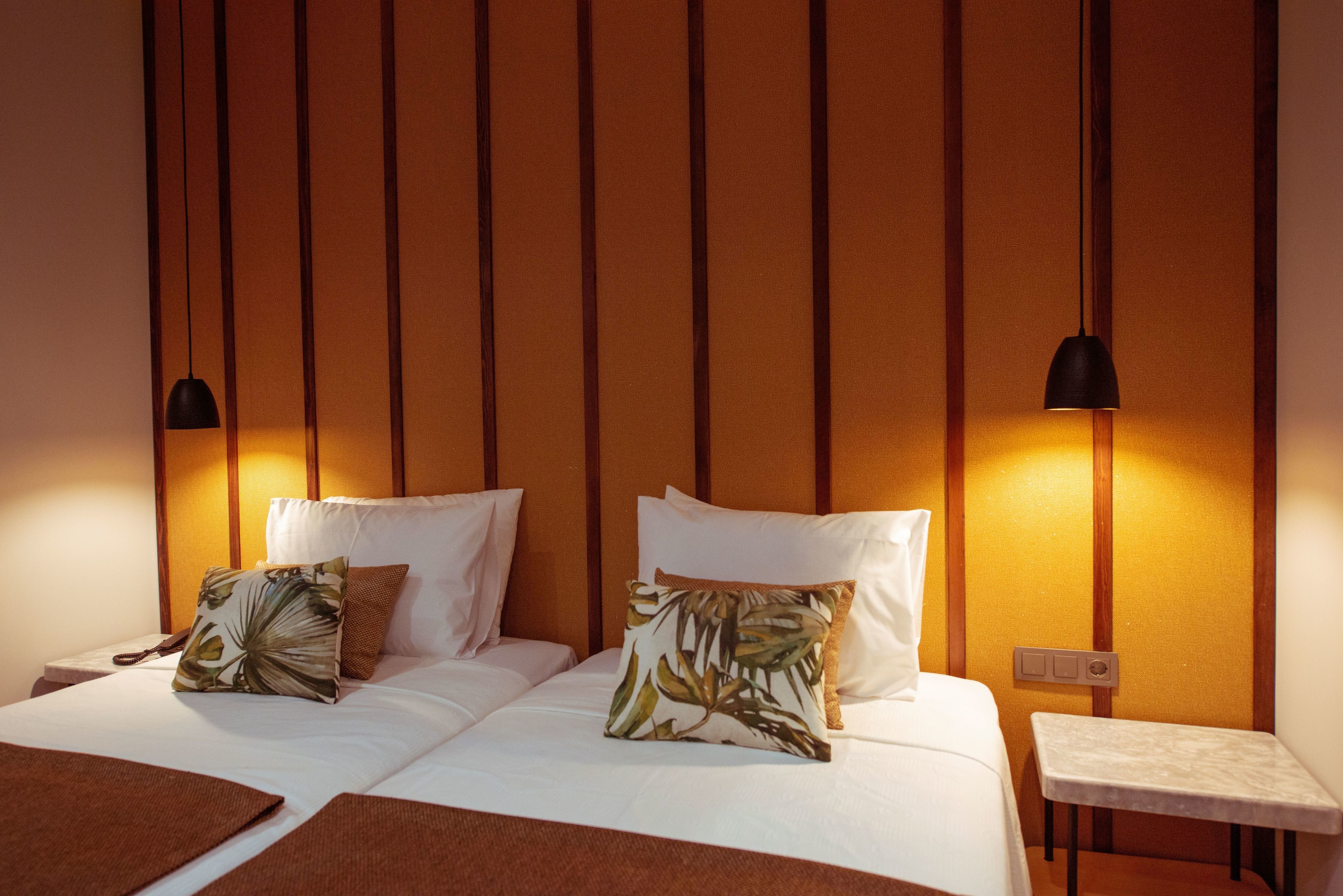 Une chambre d’hôtel avec un lit, deux oreillers, une table de chevet et une petite table.