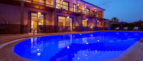 Un hotel con piscina, balcones y zona de estar al aire libre.