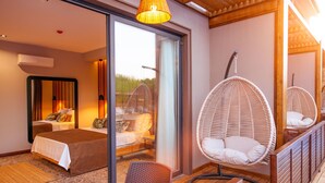 A modern bedroom with a large bed, a sitting area with wicker chairs, and a sliding glass door leading to a balcony. - Arwen Hotel (Fethiye)