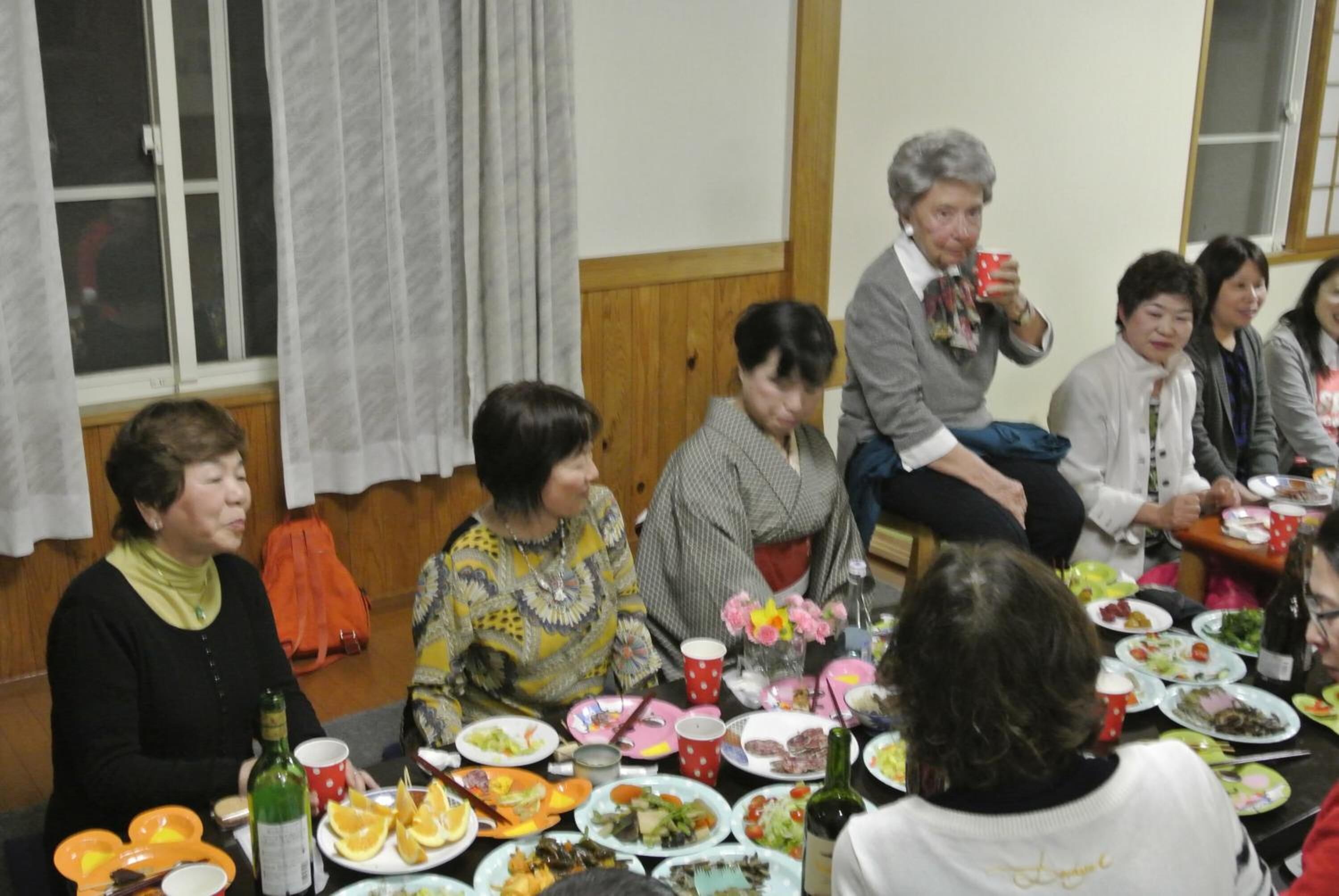 A group of people seated around a table with various dishes and drinks, suggesting a social gathering or meal.