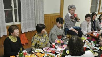 A group of people seated around a table with various dishes and drinks, suggesting a social gathering or meal.