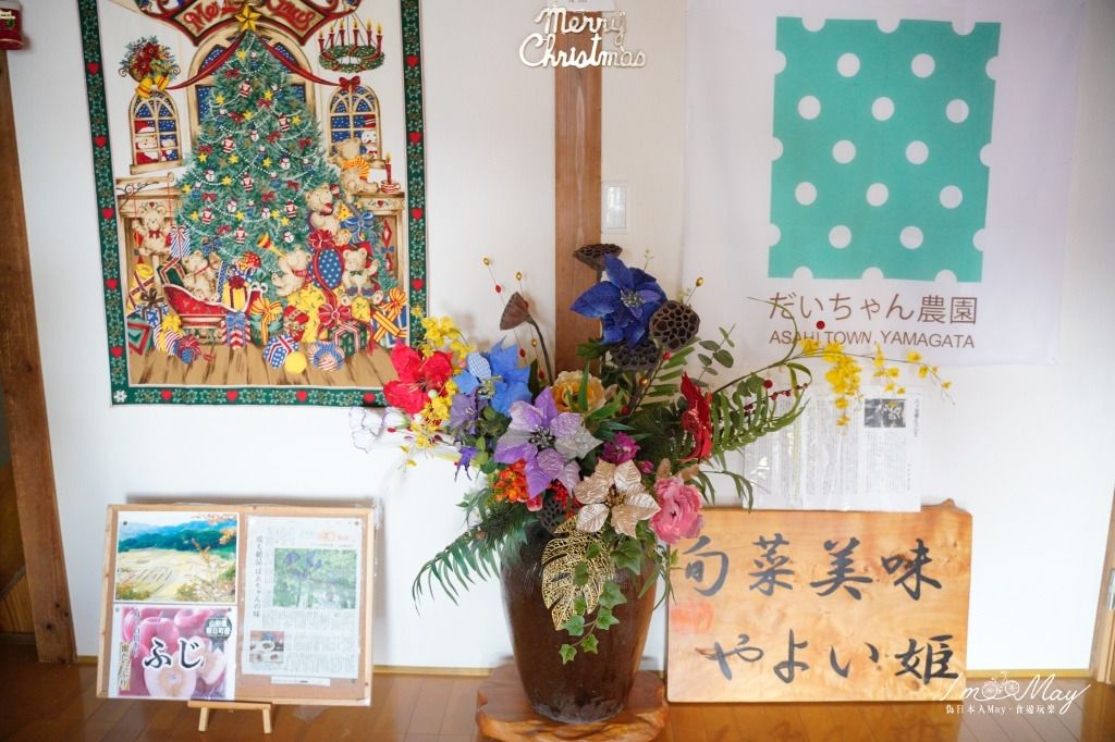 A decorated wall with a Christmas-themed painting, a bulletin board with photos, and a floral arrangement.