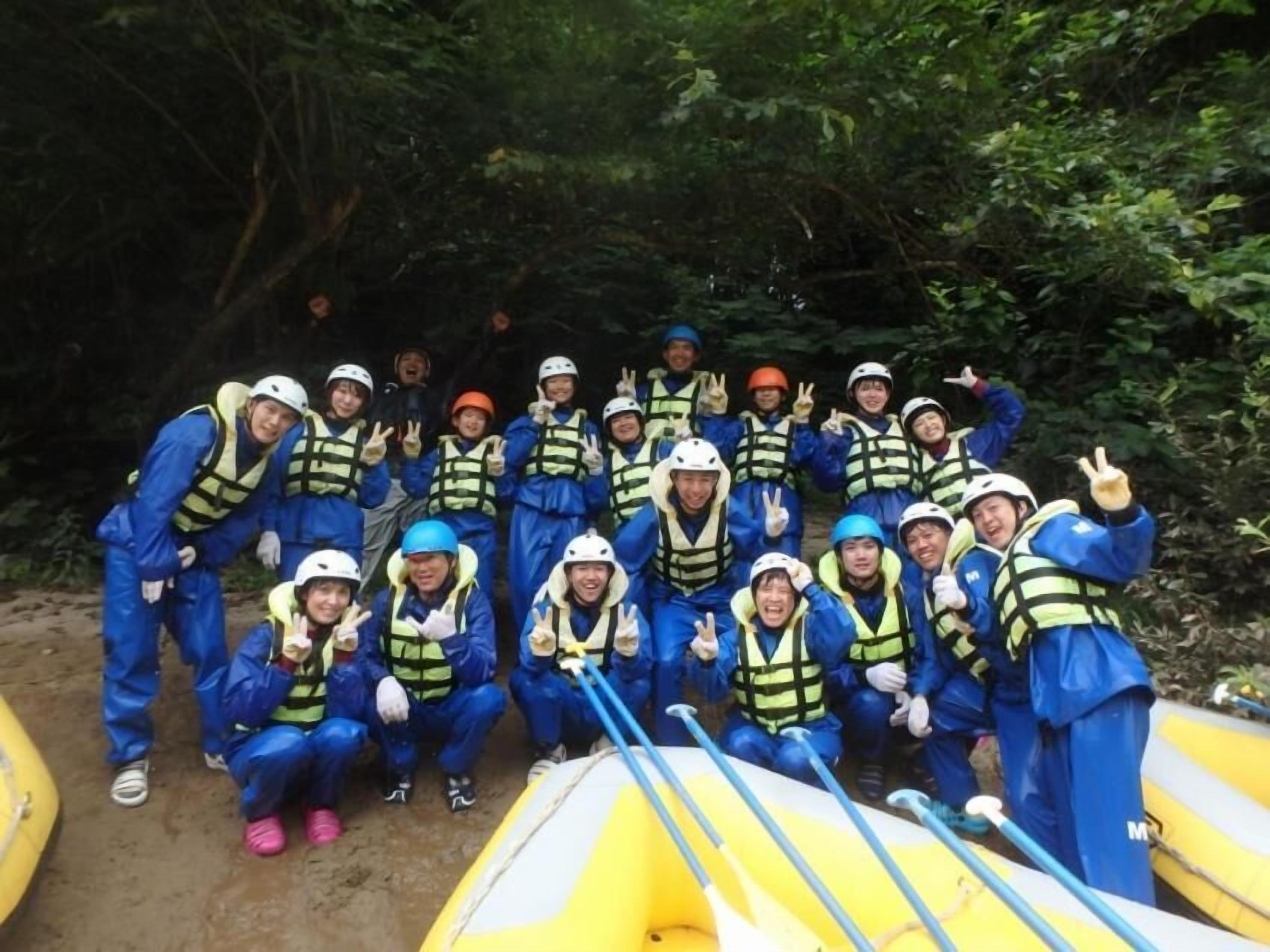 A group of people in blue and yellow safety gear posing with inflatable rafts.