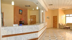 A reception area with a marble counter, wooden paneling, and a checkered floor. - Hotel El Kssour (Medenine)