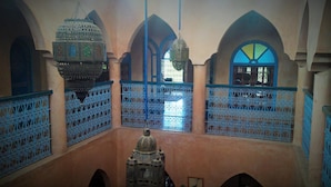An interior with arched ceilings, intricate blue metal railings, and a central dome structure.