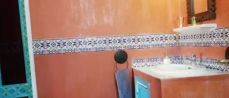 A bathroom with a tiled floor, a sink, a toilet, and a towel hanging on the wall.