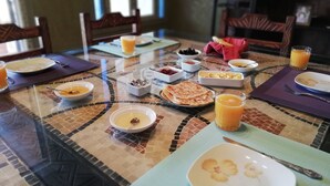 A dining table set with breakfast items including pancakes, orange juice, and bowls of food.