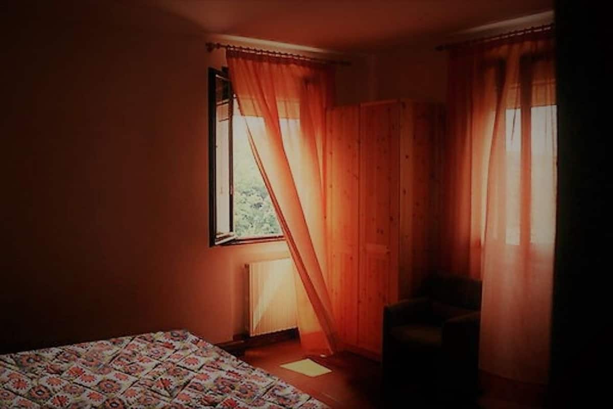 A room with a bed, a chair, and a window with curtains.