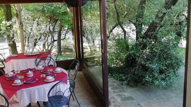 An outdoor patio with a table set for two, surrounded by greenery and trees. - Agriturismo Ai Gradoni (Teolo)