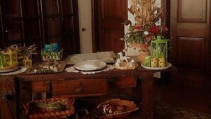 A wooden dining table with various dishes and decorations, set in a room with patterned carpet and wooden doors. - Agriturismo Ai Gradoni (Teolo)