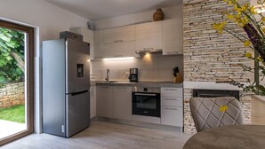 A modern kitchen with a built-in oven, a refrigerator, and a stone accent wall. - Villa Irma in Golas, Croatia (Golas)