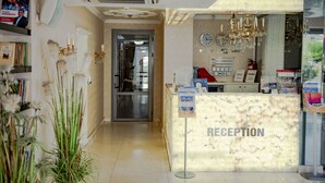 A reception area with a marble counter, a chandelier, a clock, and a sign indicating 'Moscow Beach'. - Menada Harmony Suites X Apartment (Sveti Vlas)