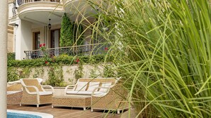 A wooden deck with wicker furniture and a pool. - Menada Harmony Suites X Apartment (Sveti Vlas)