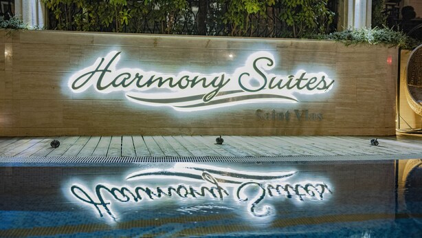 Placa de Harmony Suites, com uma piscina ao primeiro plano.