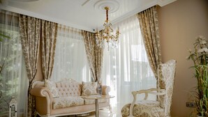 A room with a beige sofa, a round table, and a high-backed chair. - Menada Harmony Suites X Apartment (Sveti Vlas)