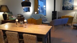 Ett mysigt vardagsrum med ett matbord i trä, flätade stolar, en soffa och en blå fåtölj.