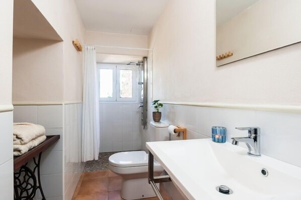 A compact bathroom with a white sink, a toilet, and a shower area. - MARGARITA SAMPOL PALOU Can Selva, village house with fantastic views as far as Pto. Alcudia (SELVA)
