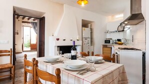 A dining area with a table set for four, a wine bottle, and a modern kitchen in the background. - MARGARITA SAMPOL PALOU Can Selva, village house with fantastic views as far as Pto. Alcudia (SELVA)