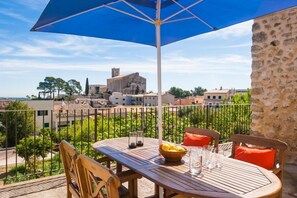 A balcony with a table, chairs, and a blue umbrella. - MARGARITA SAMPOL PALOU Can Selva, village house with fantastic views as far as Pto. Alcudia (SELVA)