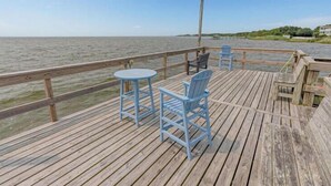 A wooden deck with a table and chairs, overlooking a body of water. - Willes-Easy walk to beach 2 suites Community Pool, Tennis and more (Duck)