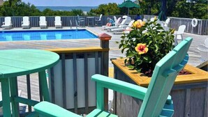 Un espace aménagé au bord de la piscine, avec une terrasse en bois, une table ronde et une chaise.