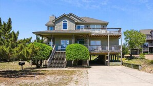 A two-story house with a front porch, a covered deck, and a staircase leading to the entrance. - Willes-Easy walk to beach 2 suites Community Pool, Tennis and more (Duck)