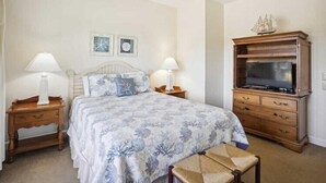Une chambre à coucher comprenant un lit, deux tables de chevet, un téléviseur et une armoire en bois.