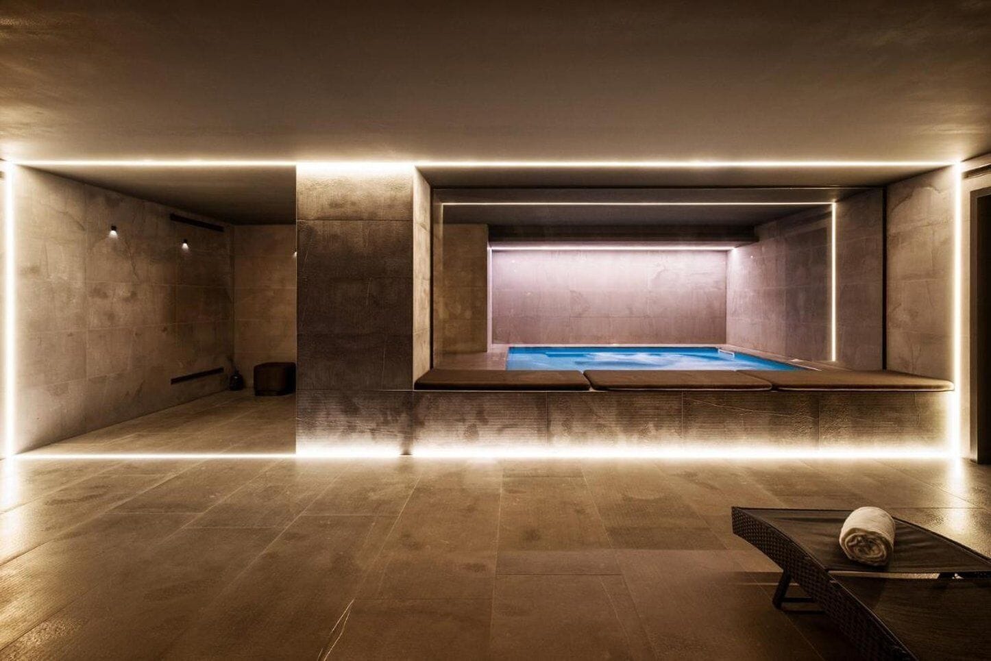 A spa room with a hot tub, wooden flooring, and a towel on a bench.