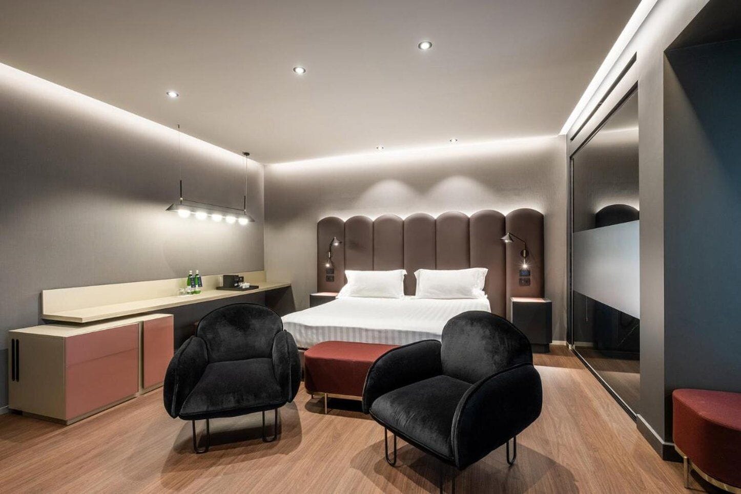 Una habitación de hotel moderna con una cama, mesitas de noche, un escritorio y dos sillas.