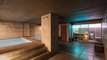 Uma área de spa moderna com uma grande banheira de hidromassagem, sauna e espaço de chuveiro com paredes de vidro.