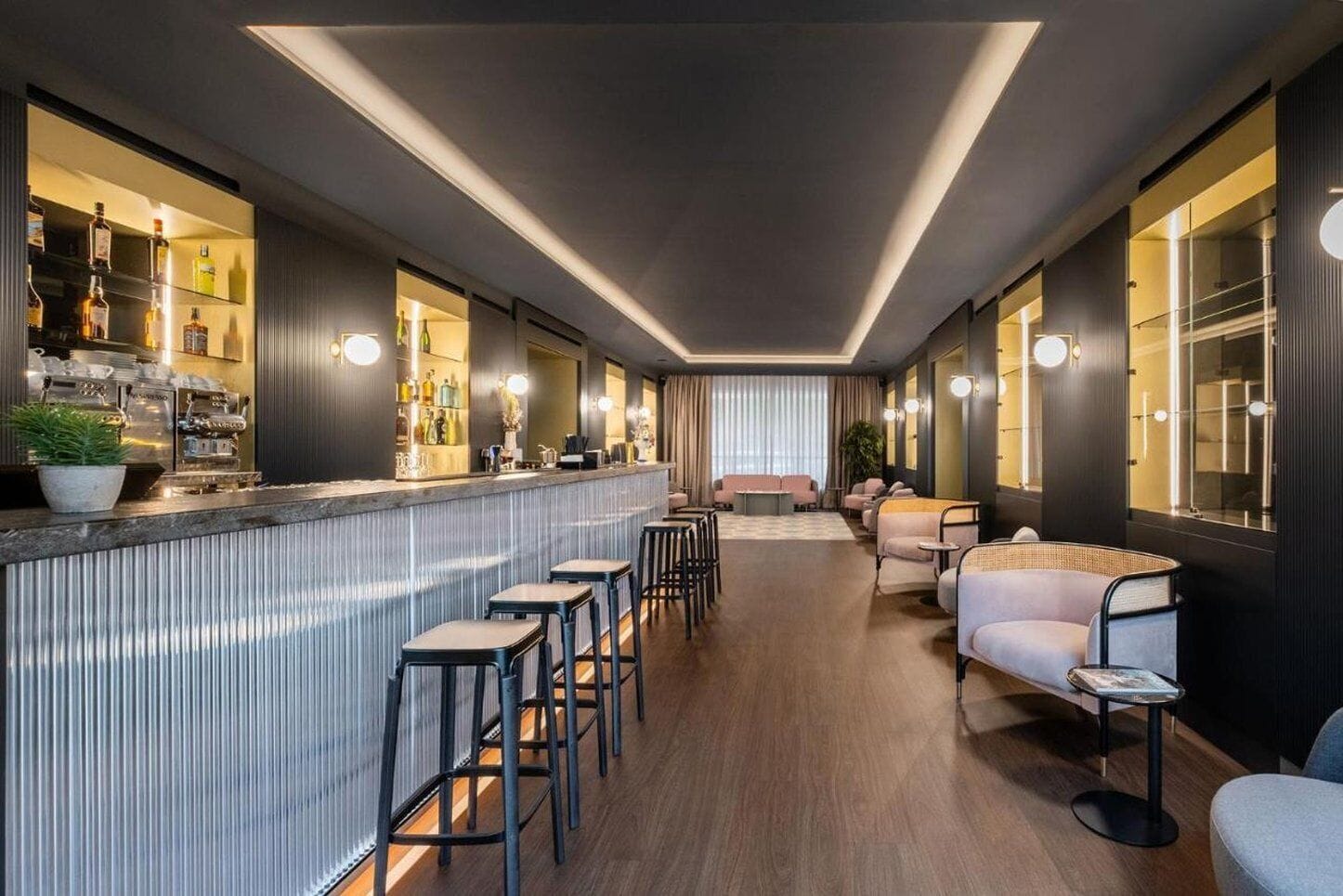 A bar area with stools, a counter, and a seating area with couches and chairs.