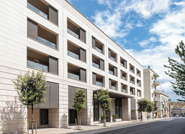 Un edificio moderno de varios pisos con fachada limpia, ventanas grandes y balcones regularmente distribuidos.