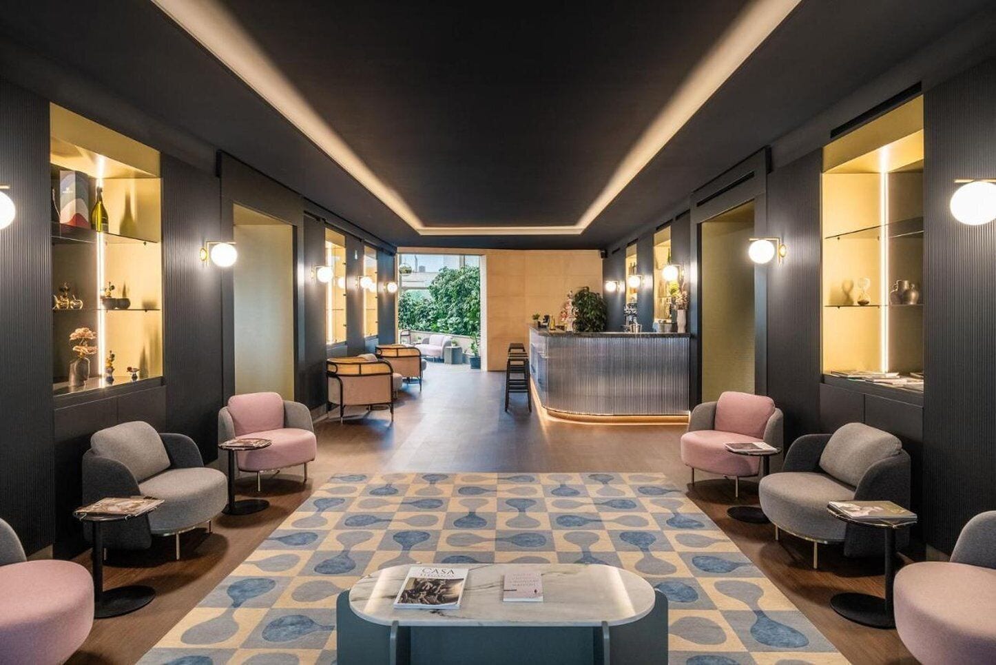 A hotel lobby with a reception desk, seating area, and a patterned floor.