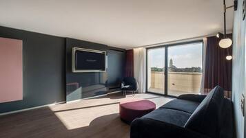 A modern living room with a large window, a flat-screen TV, a sofa, and a chair.