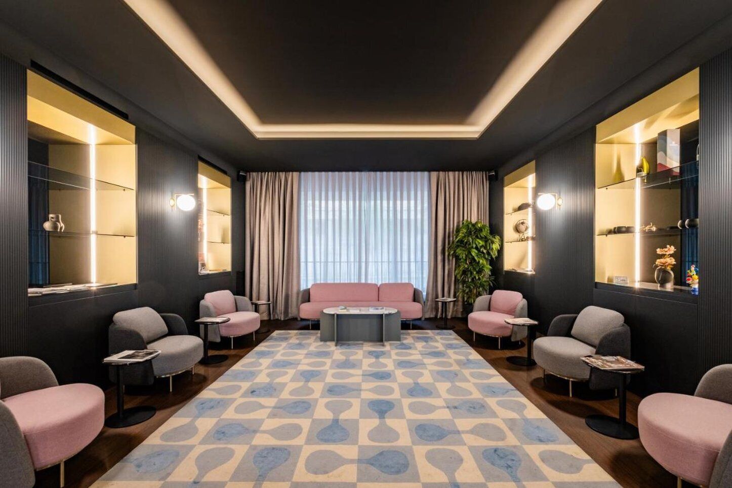 Un área de estar moderna con un sofá central, sillones y un tapiz estampado.