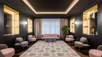 Un área de estar moderna con un sofá central, sillones y un tapiz estampado.