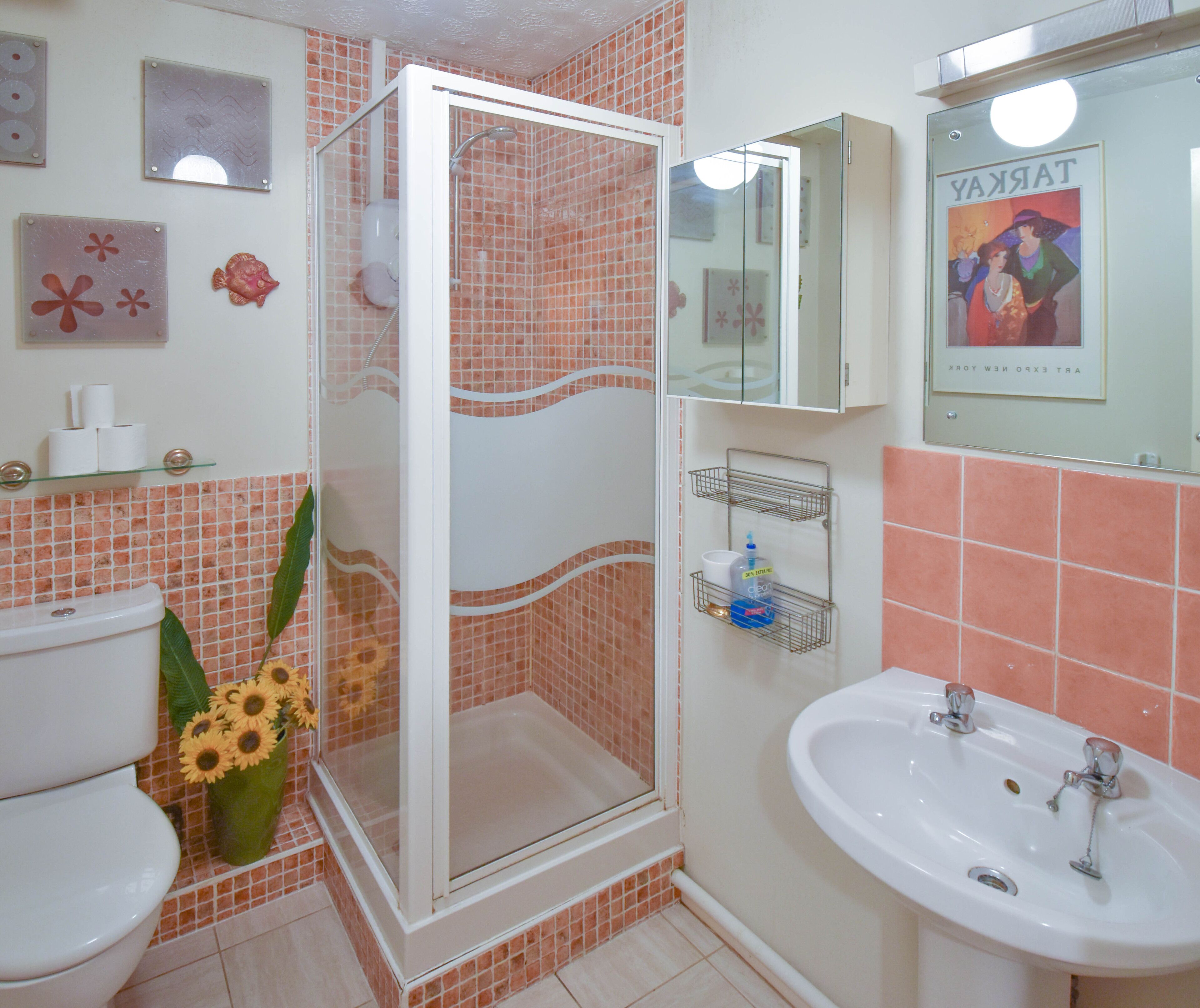 A bathroom with a glass-enclosed shower, a toilet, a sink, and a mirror.