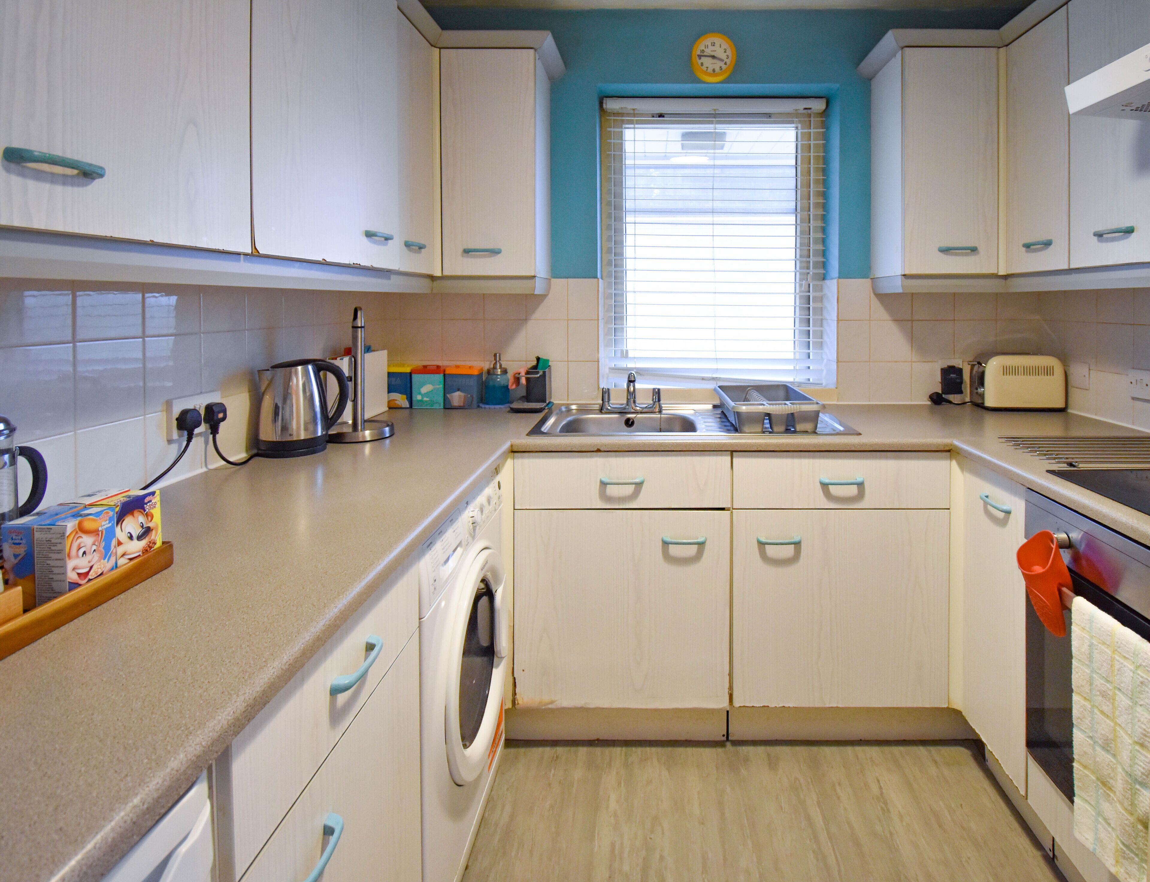 A compact kitchen with a washing machine, sink, and toaster.