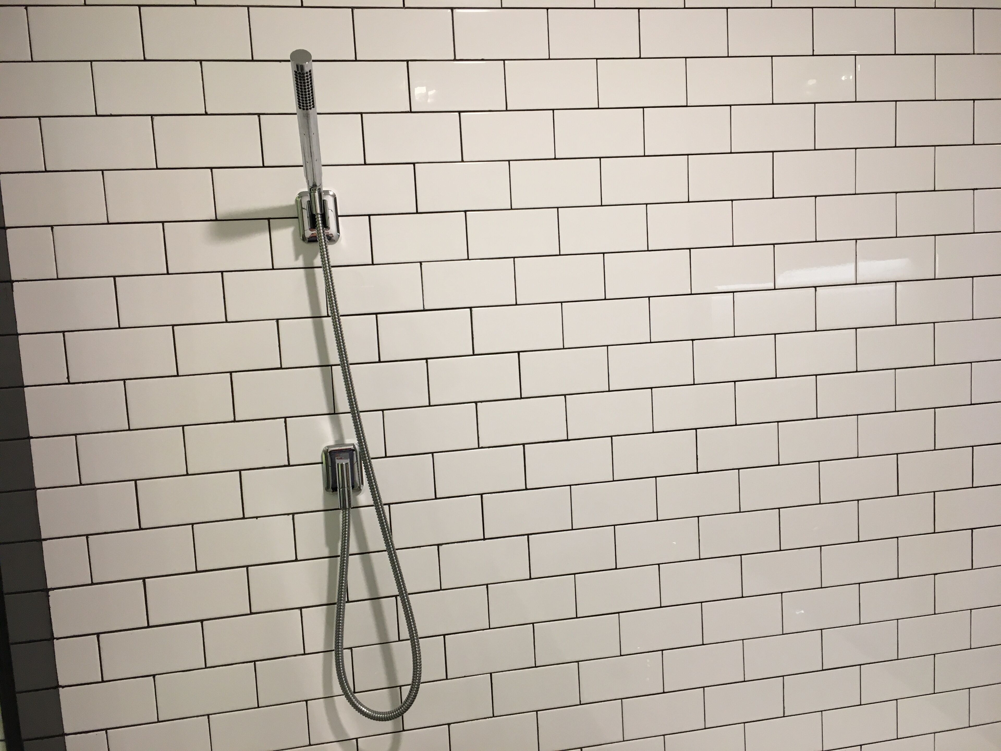 A showerhead mounted on a white tiled wall.