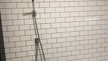 A showerhead mounted on a white tiled wall.