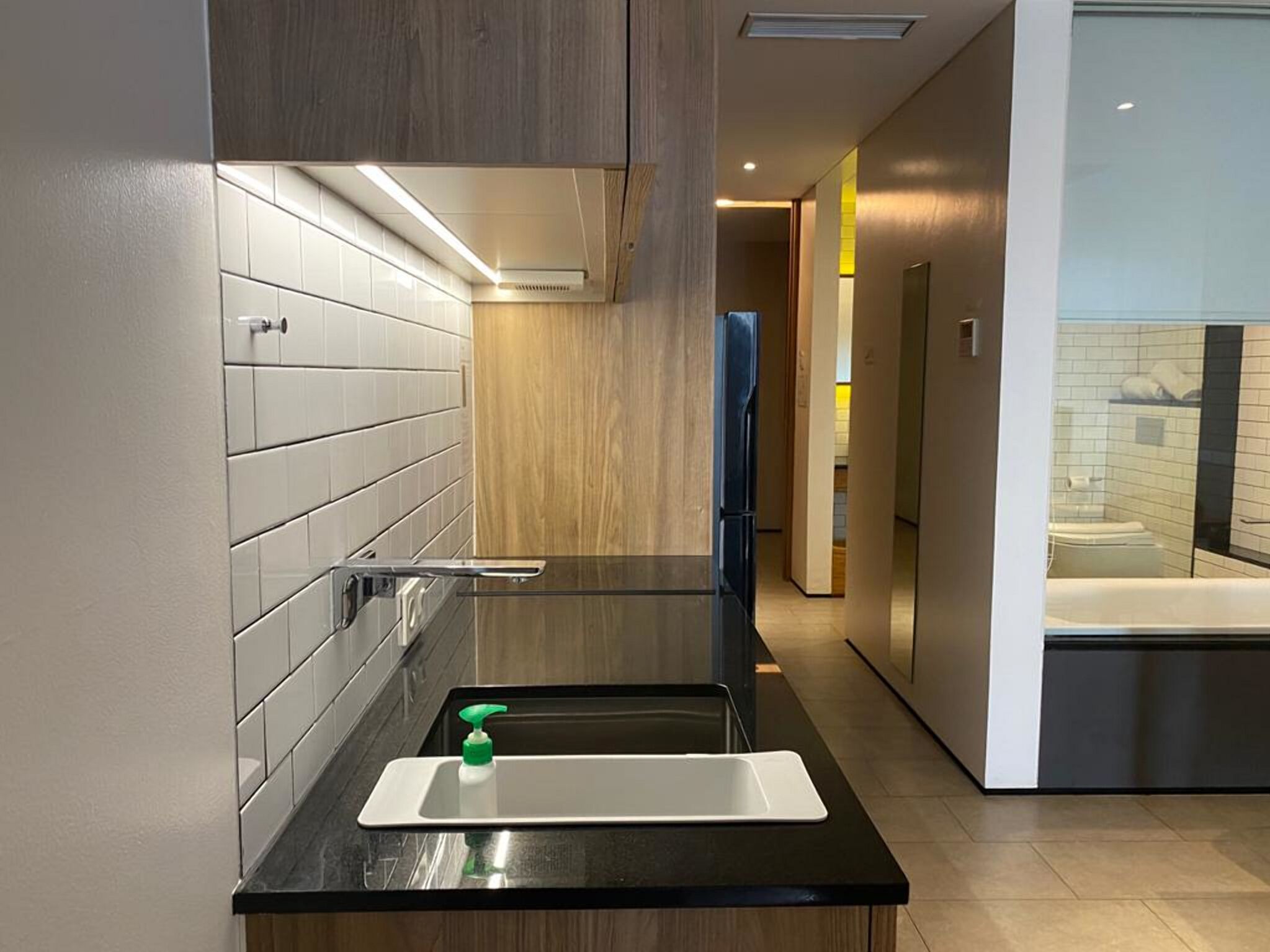 A modern bathroom with a black countertop, a white sink, and a wooden vanity.