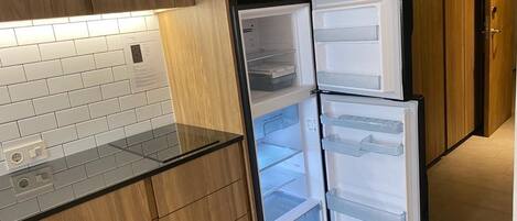 A kitchen with wooden cabinets, a microwave, and a double-door refrigerator.