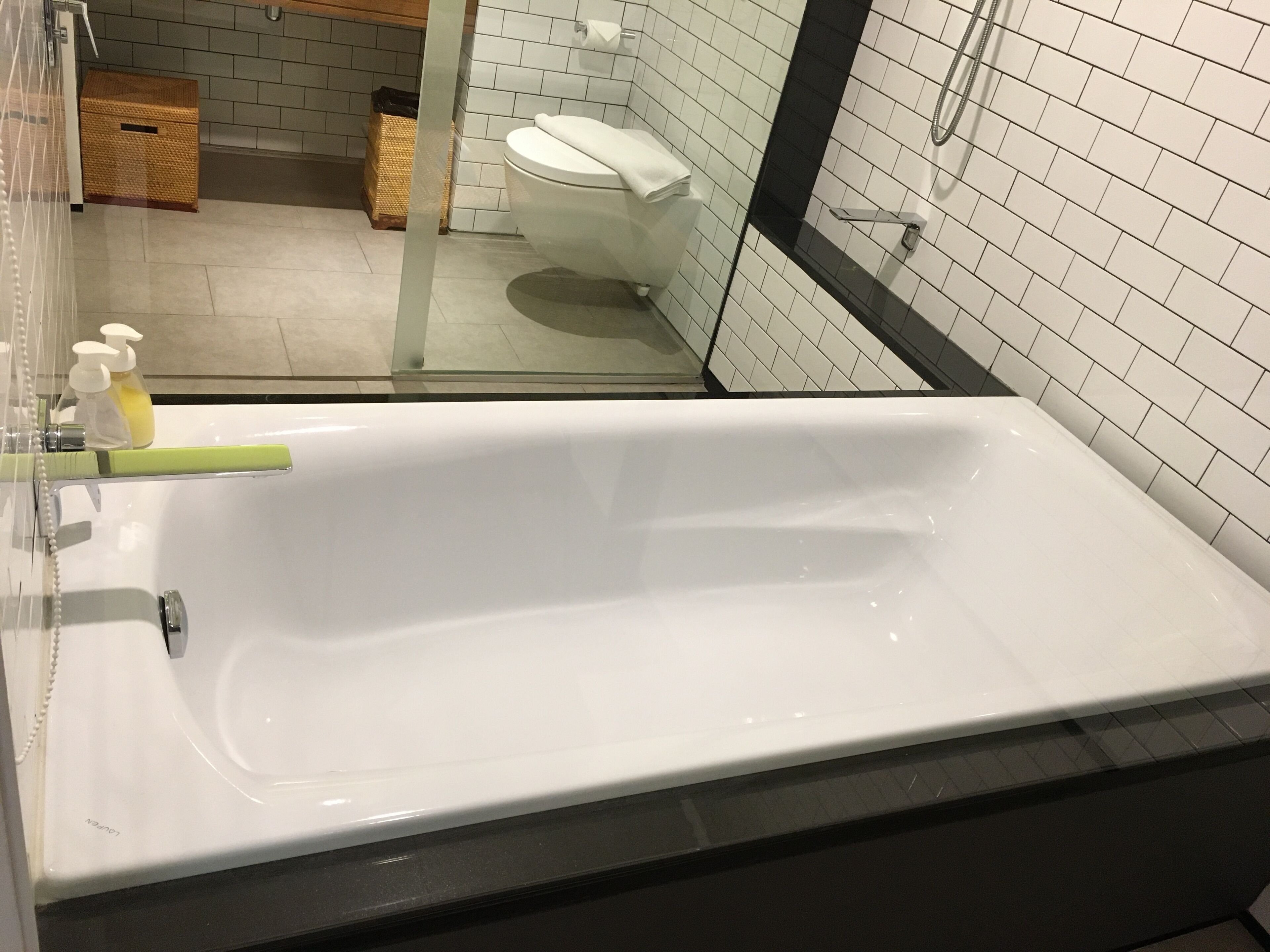 A modern bathroom with a white bathtub, a glass shower enclosure, and a toilet.
