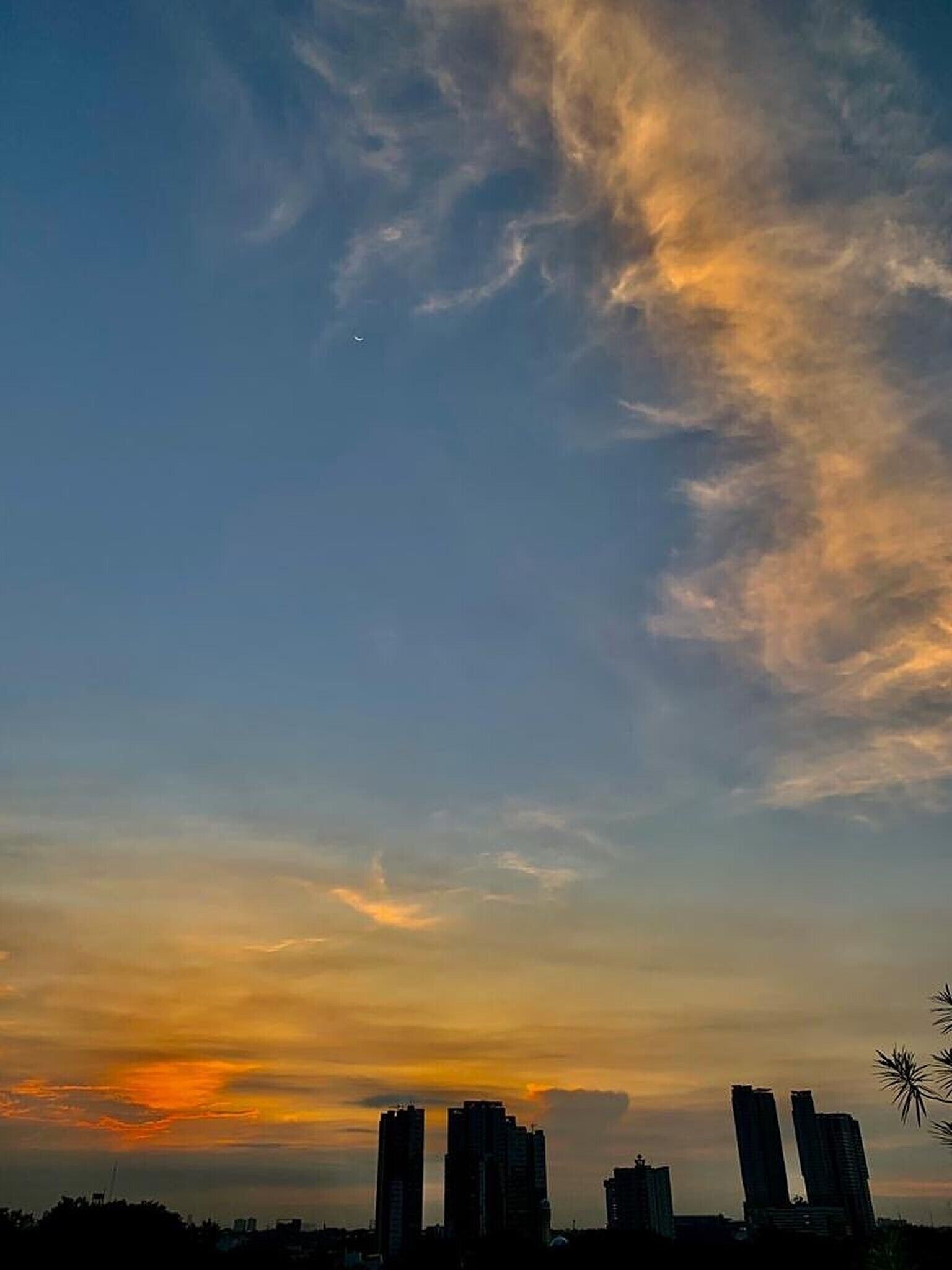 Un horizonte urbano al atardecer, con edificios altos delineados contra un cielo colorido.