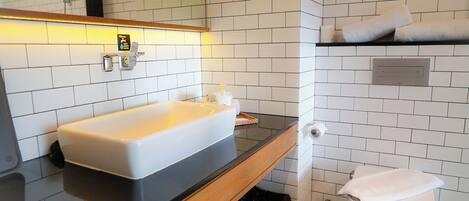 A modern bathroom with a white sink, black countertop, and white tiled walls.