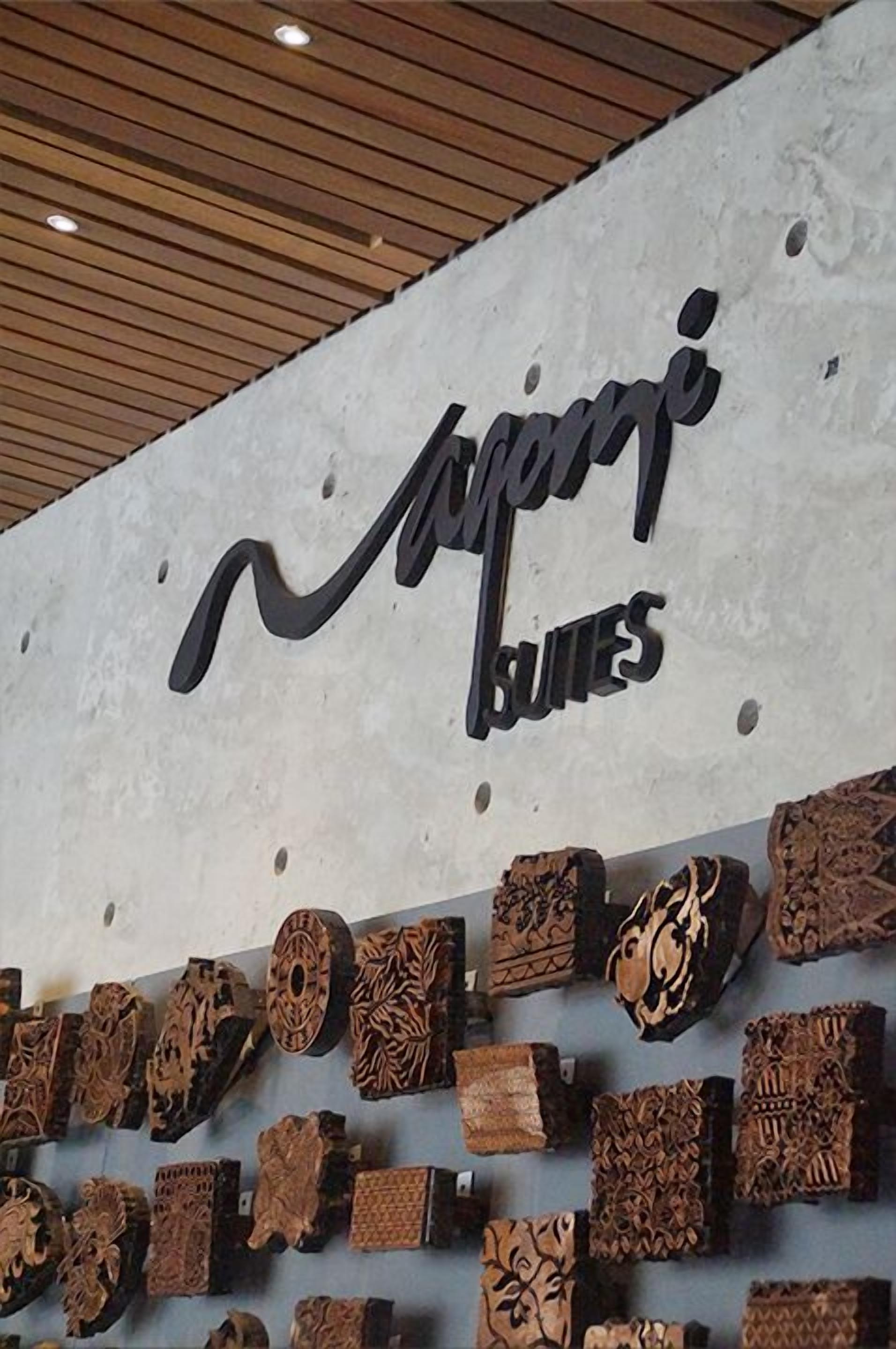 Una pared con un letrero que dice "Jampii Suites" y una exhibición de diversas tallas de madera.